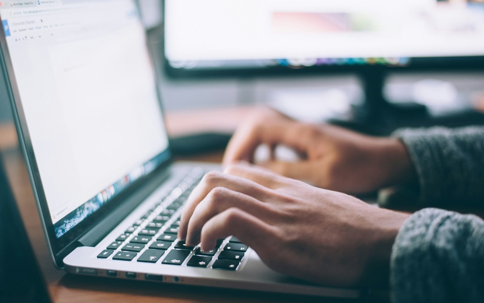 Hands reviewing a draft on a laptop